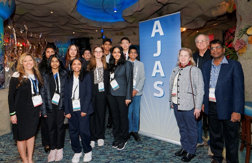 Students and adults standing in front of AJAS sign.